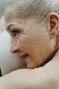 Close-up profile of an elderly woman with white hair relaxing on a towel, showcasing natural aging features.
